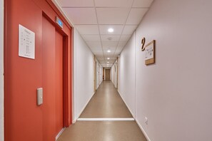 Pasillo de hotel con puertas numeradas, un detector de incendios y un cartel que indica la ubicación del conserje.