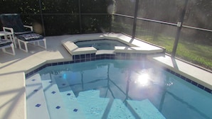 Une piscine avec un jacuzzi et des chaises longues.