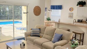 Un vaste espace de vie comprenant un grand canapé, une table basse et un coin cuisine avec un évier et un plan de travail.