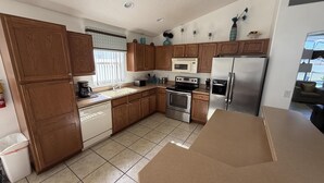 A modern kitchen with wooden cabinets, stainless steel appliances, and a large countertop. - Daisy's Den - Five Bedroom Home (Kissimmee)