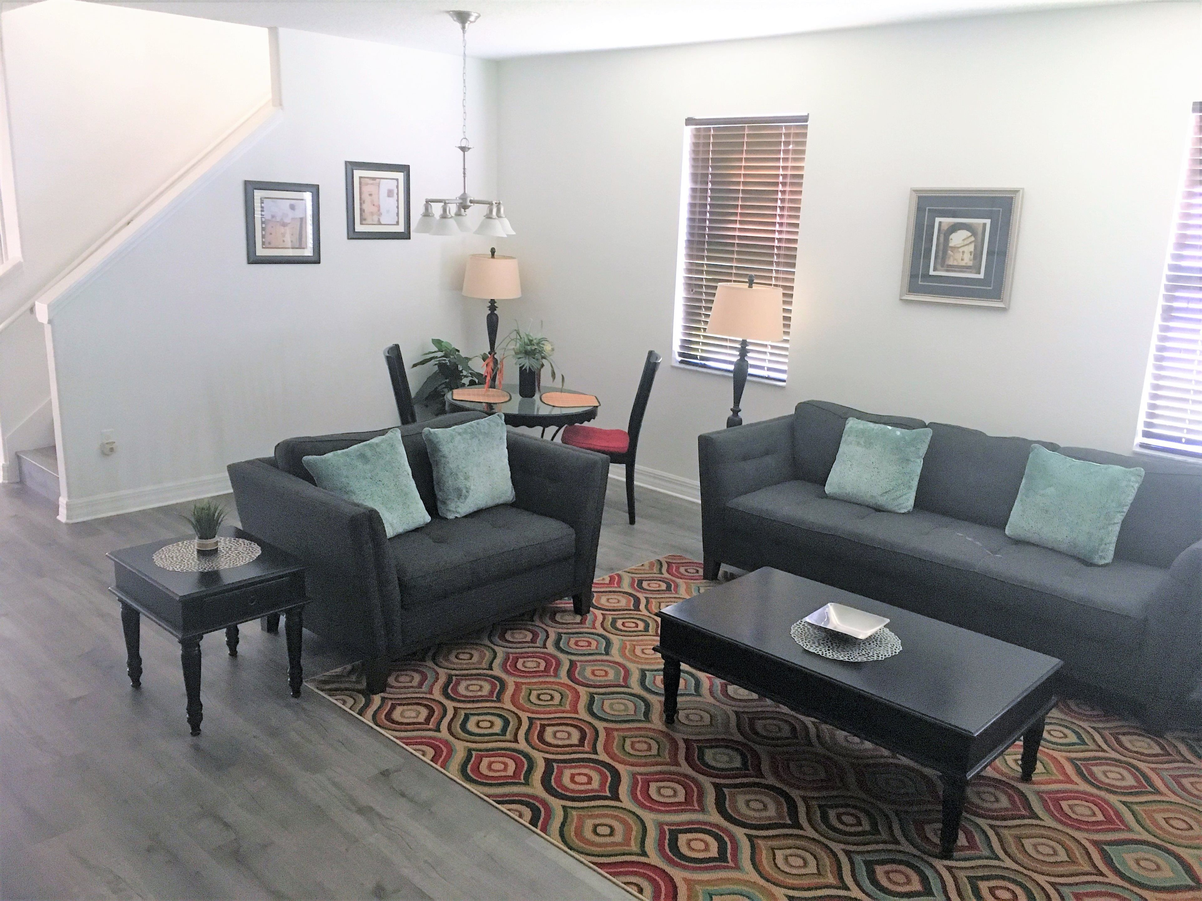 A living room with two sofas, a coffee table, a patterned rug, and a staircase.