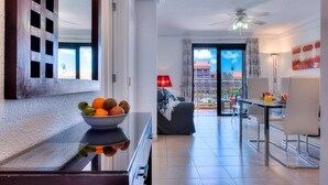 Una sala de estar moderna con comedor, un balcón que ofrece vistas a edificios y un ventilador de techo.