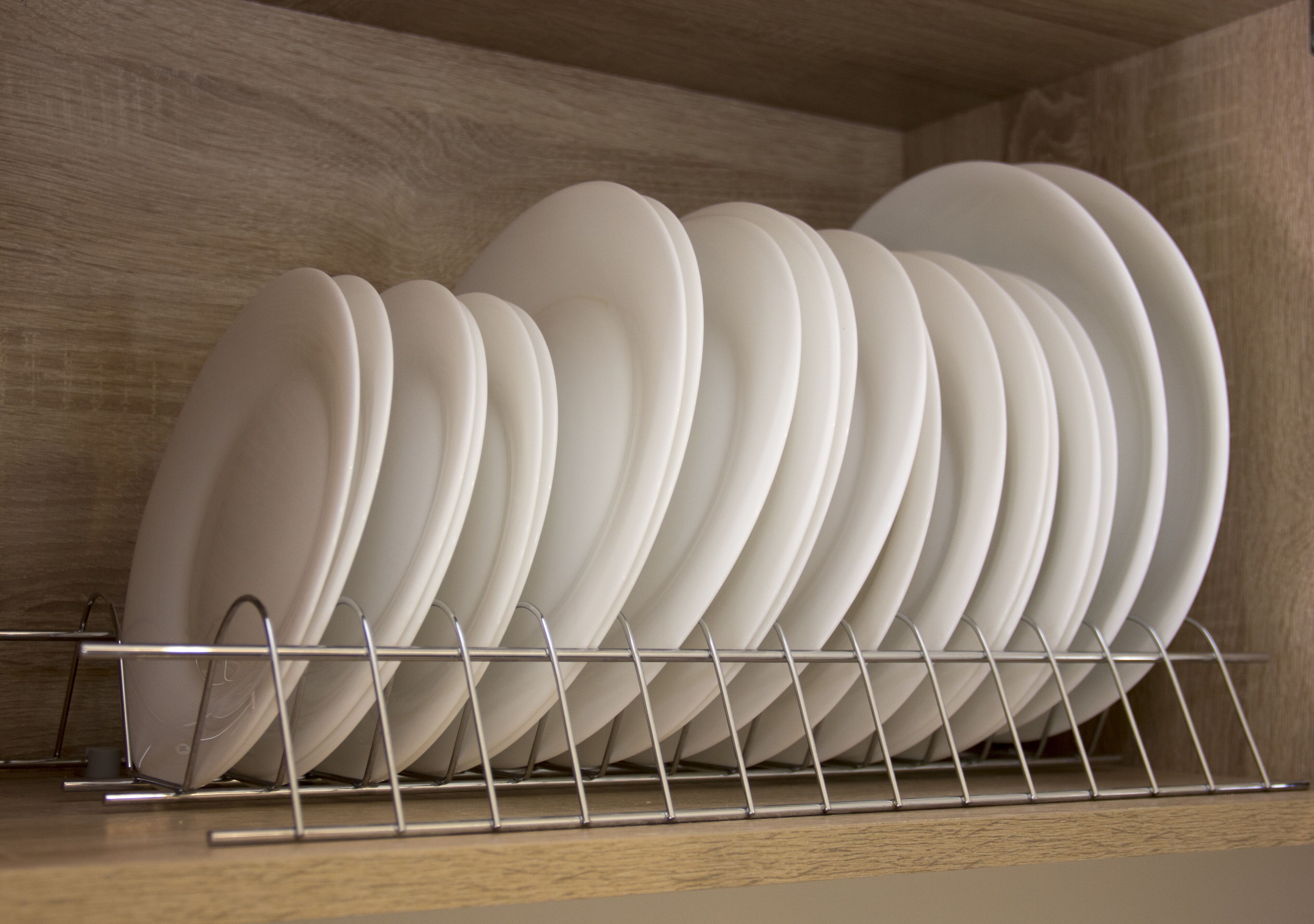 Un estante de metal con platos blancos en una cocina.