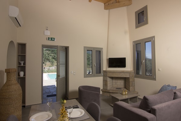 A modern living room with a fireplace, seating area, and a view of the outdoor pool.