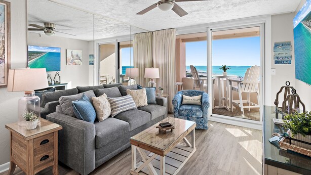 A living room with a gray couch, wooden coffee table, and a view of the ocean through large glass doors. - Gulf view unit at Jetty East! One free beach set up daily. (Destin)