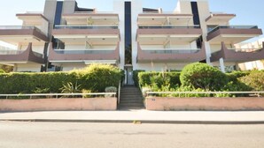 A modern multi-story building with a central staircase, surrounded by greenery and a clear sky. - Antares by Interhome (Cavalaire)