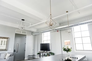 A modern, spacious room with a large table, a flat-screen TV, and a sofa.