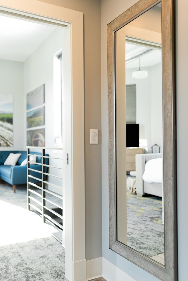 Une chambre d’hôtel avec un grand miroir, un lit, une commode et un canapé bleu.