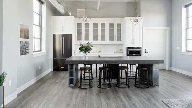 A modern kitchen with a central island, bar stools, a refrigerator, and pendant lighting. - South Flat Luxury Suite - Full Kitchen, Adjustable King Bed, Full Bed in Loft (Logan)