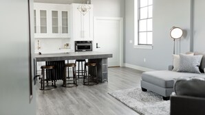 A modern kitchen with a bar area, white cabinetry, and a large window. - South Flat Luxury Suite - Full Kitchen, Adjustable King Bed, Full Bed in Loft (Logan)