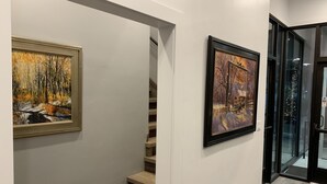 A staircase with two framed paintings on the walls, a glass door leading outside, and a black doormat at the bottom. - South Flat Luxury Suite - Full Kitchen, Adjustable King Bed, Full Bed in Loft (Logan)