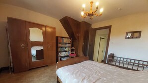 Una camera da letto con un letto grande, un armadio in legno, una libreria e un lampadario.