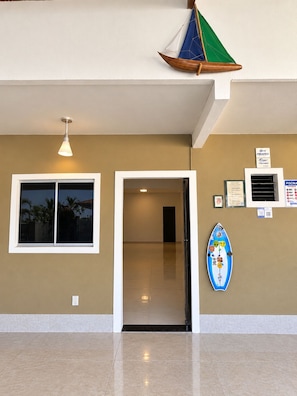 A hotel lobby with a large window, a door, and a wall-mounted surfboard decoration.