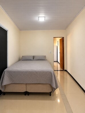 Un dormitori amb un llit, una porta i un passadís que condueix a una altra habitació.