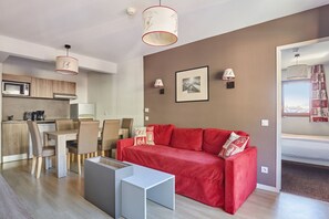 Ein stilvoller Wohnraum mit einem roten Sofa, einem Essbereich und einer Küche.
