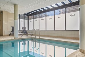 A swimming pool area with lounge chairs and a glass ceiling. - Appartement dans les Montagnes | Navette Gratuite (Serre Chevalier)