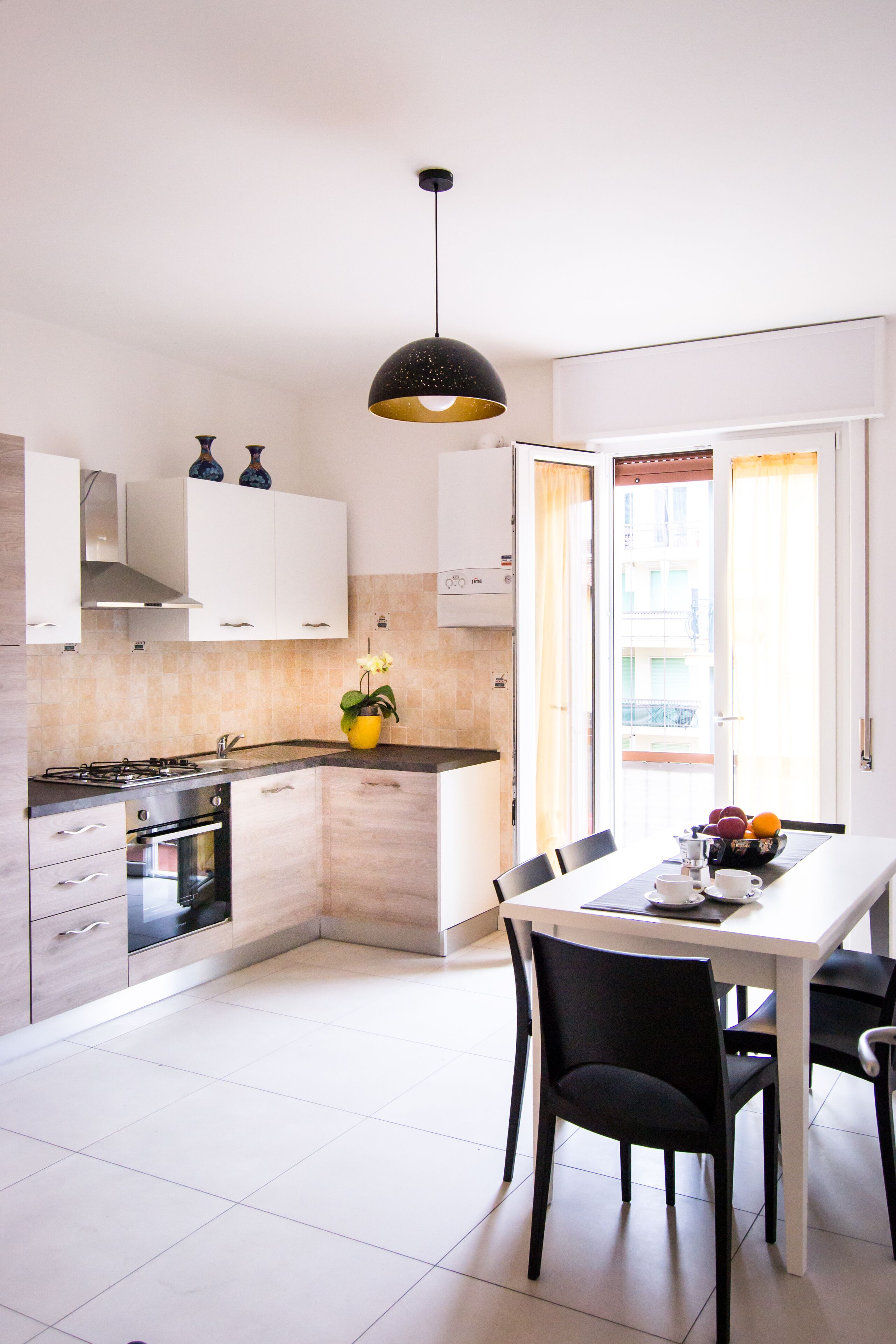 Eine moderne Küche mit weißen Schränken, einem Gasherd und einem Essbereich mit Tisch und Stühlen.