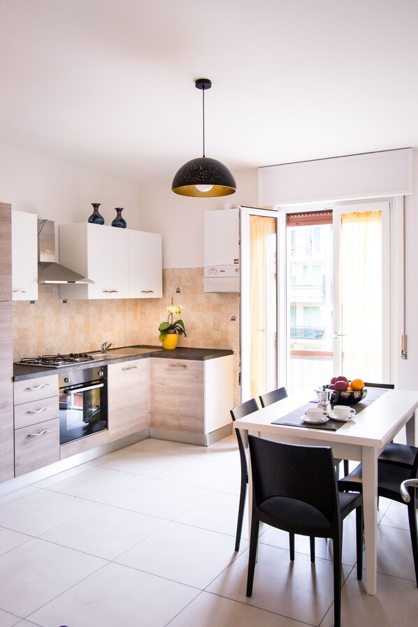 A modern kitchen with white cabinets, a gas stove, and a dining area with a table and chairs.