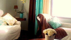 A hotel room with two beds, a coffee table with a book, a potted orchid, and a window with curtains. - Villa de Sao Paulo - (Funchal)