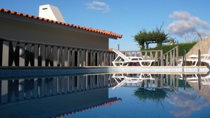 A swimming pool with a tiled deck, lounge chairs, and a clear blue sky. - Villa de Sao Paulo - (Funchal)