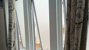 A room with a large window, white walls, and patterned curtains. - Hotel Syariah Mama Cengkareng (Jakarta)