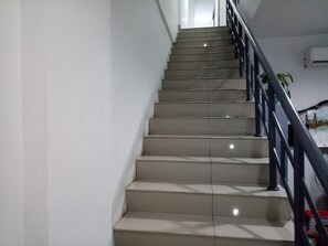 A staircase with a handrail, leading to an upper floor.