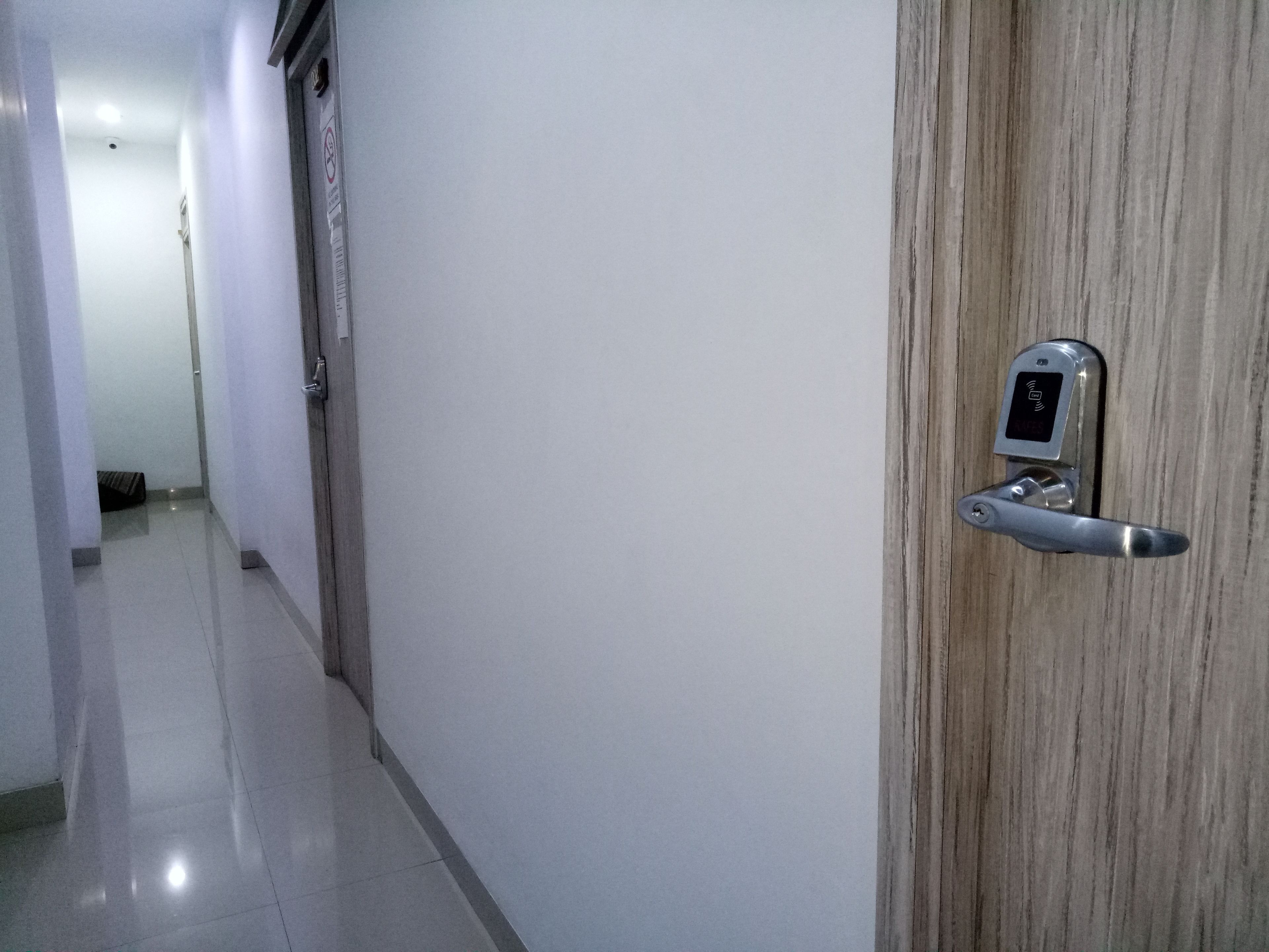 A hallway with a modern door equipped with a digital lock and a keyhole.