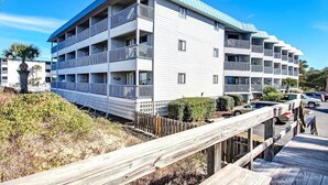 Un hôtel à plusieurs étages doté de balcons, d’une terrasse en bois et surplombant un ciel d’un bleu limpide.