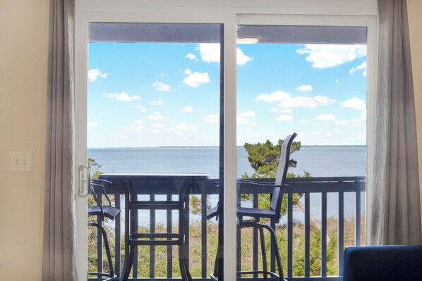 A balcony with a view of the sea, featuring two chairs and a table.