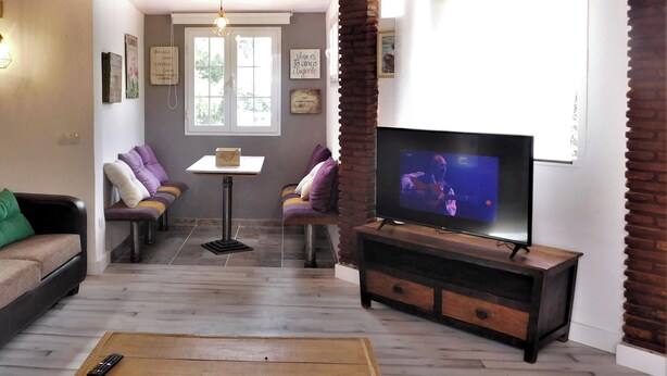 Ein gemütliches Wohnzimmer mit Holzboden, einer Couch, einem Couchtisch und einem Fernseher.