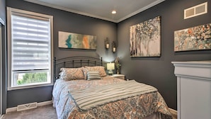 A bedroom with a bed, a nightstand, a lamp, and artwork on the walls. - Walk to Parks & Dining: Spacious Ligonier Home! (Ligonier)