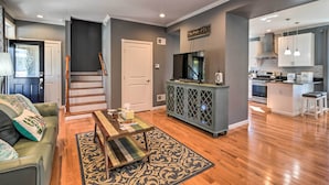 A modern living room with a sofa, coffee table, and patterned rug. A staircase leads to another level. - Walk to Parks & Dining: Spacious Ligonier Home! (Ligonier)