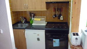 A compact kitchen with a refrigerator, stove, and toaster.