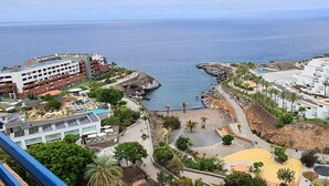 A coastal resort with a rocky shoreline, a sandy beach, and a pool area.