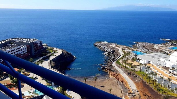 A coastal hotel with a pool, beach access, and rocky cliffs.