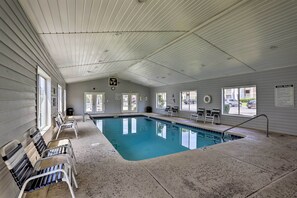 An indoor swimming pool with a tiled floor, benches along the sides, and a sign indicating pool rules.