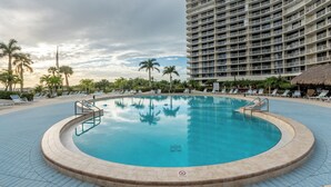 A large, circular swimming pool with a no diving sign, surrounded by lounge chairs and palm trees, with a high-rise building in the background. - South Seas Tower Two # 810.  Condo with Balcony, Beach, Pool and Fitness Facility. (Marco Island)
