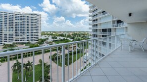 Ein Balkon mit Blick auf einen modernen Gebäudekomplex, einen Parkplatz und Grünflächen.
