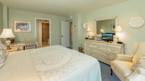 Ein Schlafzimmer mit Bett, Schminktisch, Stuhl und Fernseher.