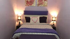 A neatly made bed with a heart-shaped pillow, two bedside lamps, and a floral artwork above the headboard. - Apartment very close to Gran Via Sol WiFi Museums  (Madrid)