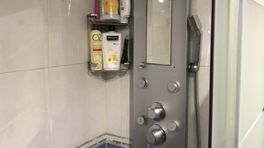 A bathroom with a glass shower enclosure, a vanity with toiletries, and a tiled floor. - Apartment very close to Gran Via Sol WiFi Museums  (Madrid)