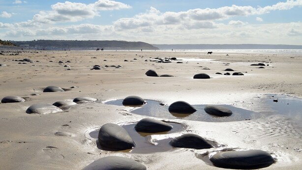 A beach with scattered rocks and a distant shoreline. - 2 bedroom accommodation in Buckland Brewer, near Bideford (Buckland Brewer, near Bideford)