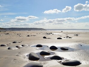 A beach with scattered rocks and a distant shoreline. - 2 bedroom accommodation in Buckland Brewer, near Bideford (Buckland Brewer, near Bideford)