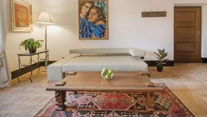 Un salon avec un canapé, une table basse, un tableau et une porte.