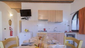 Une cuisine compacte avec un coin repas, un téléviseur fixé au-dessus du comptoir et une fenêtre avec des rideaux.