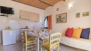 Une cuisine chaleureuse avec une table à manger, des chaises et un canapé agrémenté de coussins colorés.