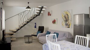 En moderne stue med trappe, sofa, spisebord og køleskab.