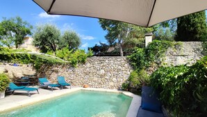 En klar swimmingpool med liggestole og en stenvæg.