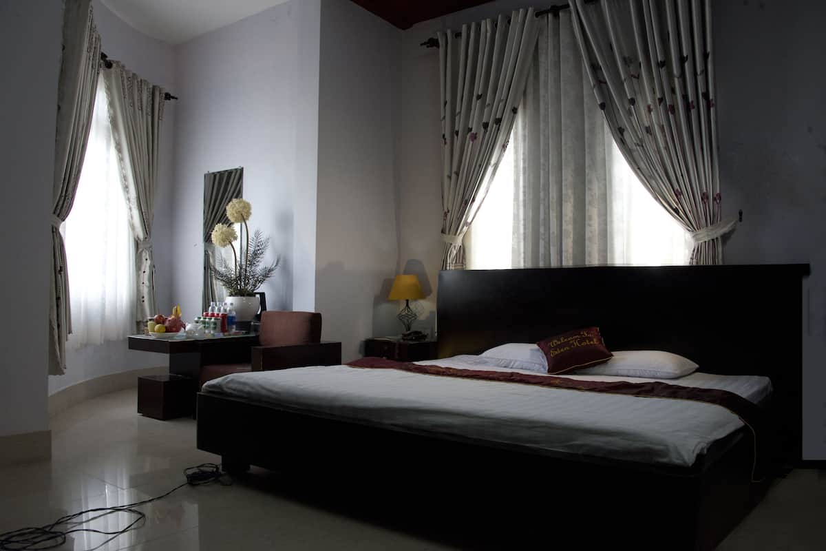 Une chambre d’hôtel avec un grand lit, un bureau avec une lampe et une chaise.