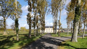 A pathway leading to a building surrounded by trees. - GITE: Country house, near the landing beaches, with table football. (Le Molay-Littry)